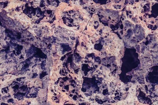 Abstract nature real photo background. Macro close up details dry rock crack stone solid foamy formations or lava volcanic, pumice texture ancient lunar style. Light pink purple gray vintage stock.