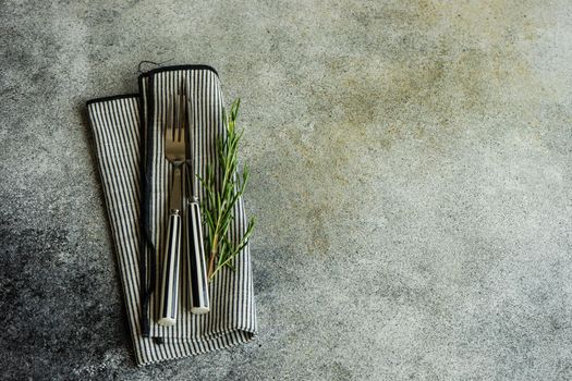 Cutlery set with textile napkin and silverware on concrete table