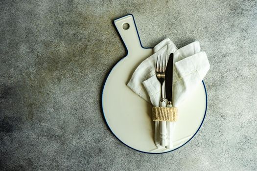 Cutlery set with textile napkin and silverware on concrete table