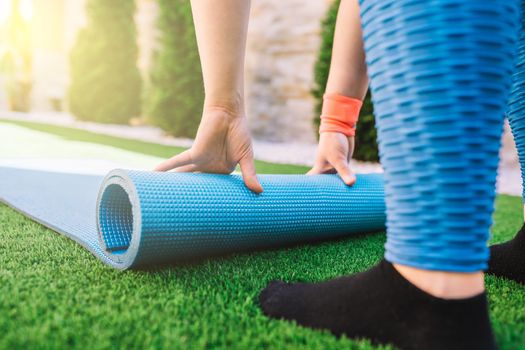 detail shot of a young woman, preparing to perform relaxation exercises, on a mat. unrecognisable girl doing sports exercises at home. concept of health and well-being. concept of health and wellness. natural light in the garden.