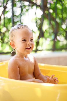 Little girl laughs in a bowl of water. High quality photo