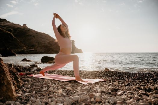 Young woman with black hair, fitness instructor in pink sports leggings and tops, doing pilates on yoga mat with magic pilates ring by the sea on the beach. Female fitness daily yoga concept