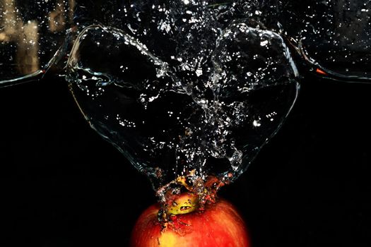 Red apple splashes in the water on black background