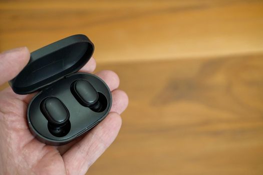 Wireless earphones with charge case in man hand close up view