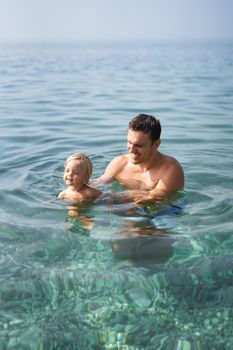 Smiling dad teaching little girl to swim. High quality photo