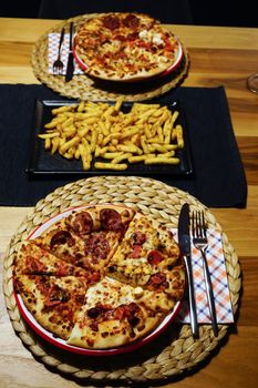 Homemade pizza and french fries on wooden table