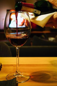 Pouring red wine in the glass close up view