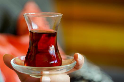 Woman holding thin belly glass of turkish tea in hand close up view