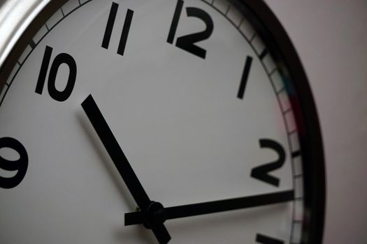 Wall clock with white base and black dials close up view