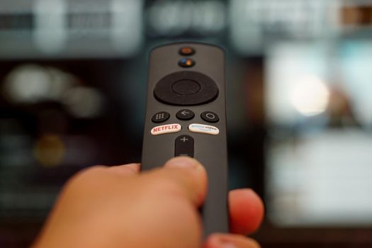 30 September 2021 Eskisehir Turkey. Remote control in man hand with netflix and amazon prime buttons on it with shallow depth of field