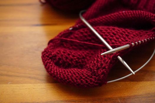 Wool knitting on wooden table close up