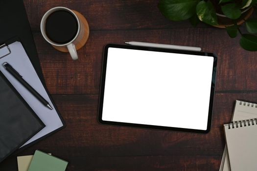 Flat lay digital tablet, notebooks, coffee cup and houseplant on wooden office desk.