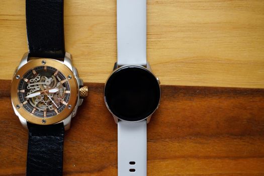 Analog and smart watches on wooden background with copyspace