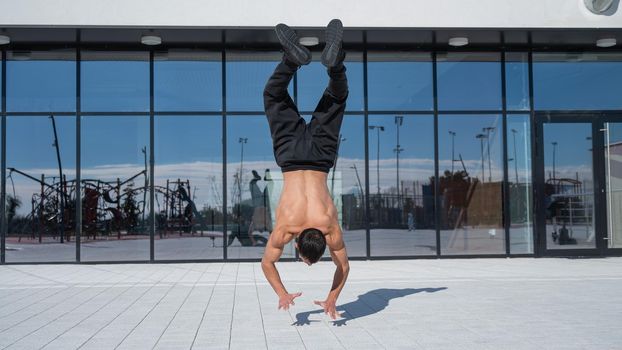 A man doing a handstand outdoors against of panoramic windows