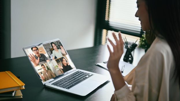 Young businesswoman chatting with colleagues online, video call via computer laptop at home office.