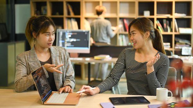 Two young female software programmer or coder discussing detail of project developing website design and coding technologies.