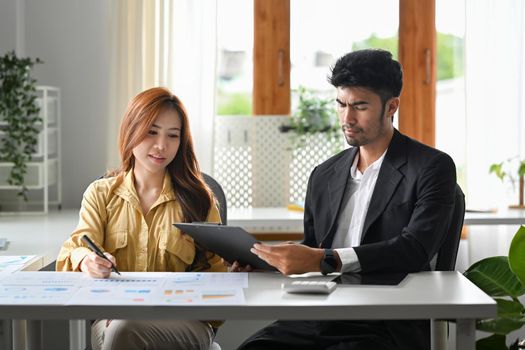 Attractive businesswoman explaining new project and discussing corporate business plan with her colleague.