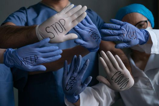 Team Of Medical Workers Shows Inscriptions Written By Black Marker On Their White And Blue Gloves, Unrecognizable People Show Open Palms With Titles, Quarantine Concept, Close Up Shot