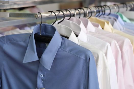 Men's plaid shirts in different colors on hangers in a retail shop