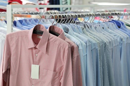 Men's plaid shirts in different colors on hangers in a retail shop