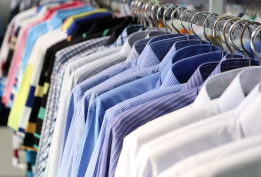 Men's plaid shirts in different colors on hangers in a retail shop