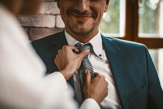 Business Woman Straightens Tie To Her Male Colleague, Woman Standing With His Back In Foreground, Selective Focus On Smiling Well-Dressed Caucasian Man, Close Up Shot, Toned Image