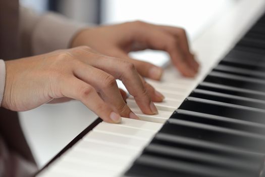 Close up of the hands of a young woman playing piano