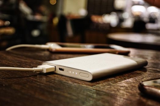 Powerbank charging smartphone close up view on wooden background