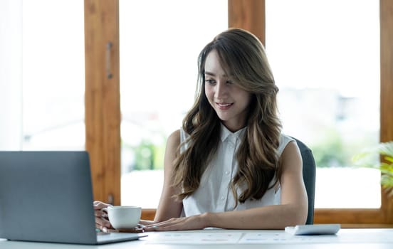 Young Asian businesswoman is happy to work at the modern office using a computer in the office..