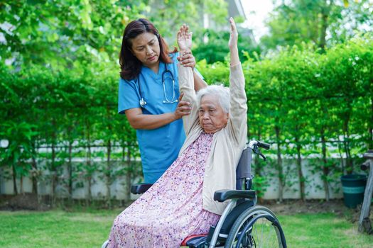 Asian elderly woman disability patient exercise on wheelchair with doctor in park, medical concept.