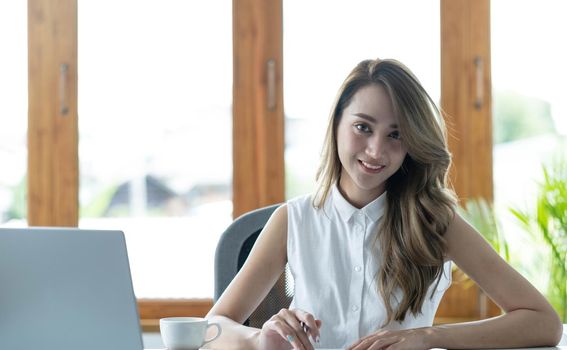 Young beautiful woman using her laptop while sitting in a chair at her working place..