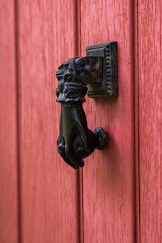 Red old door with doorknocker Metal arm of woman or man