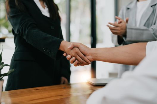 Millennial businessmen colleagues shaking hands on meeting in office, diverse enterpreneurs striking good deal, multiethnic teammates succeed in common project work.