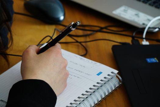 Home office working woman with pen in hand on a messy desk