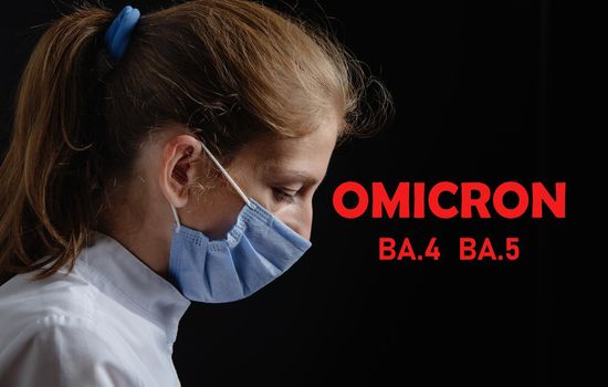 A female doctor or nurse is tired and upset at work. The health worker is saddened. Photo of a woman wearing a medical protective mask against a black background. Pandemic covid 19 concept, Omicron Ba.4 and Ba.5. Depressed surgeon leaning on desk at hospital. Healthcare workers in the Coronavirus Covid19 pandemic