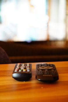 Two television remote controllers on wooden background image with shallow depth of field