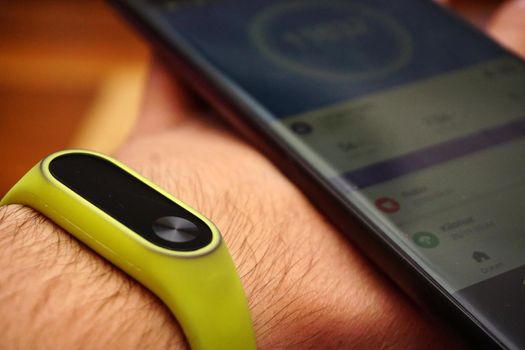 Smartphone and fitness activity tracker bracelet on the wrist close up view
