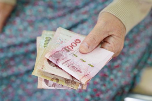 Asian elder senior woman patient holding banknotes money in her hand, Cost of living and medical care.