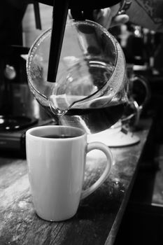 Barista pouring filter coffee in mug close up view