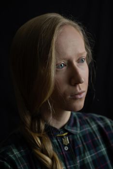 A young Ukrainian woman blonde with a braided braid in the studio close up on a black isolated background and a pendant Trident. The concept of stop war in Ukraine from the Russian invaders