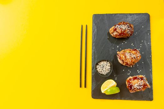 Chicken teriyaki is a classic Asian dish. Top view, flat lay and blank space for text on the bright yellow background. Teriyaki chicken is a traditional Japanese frying method using a sweet sauce common in Japanese cuisine.