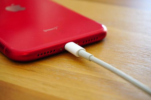 30 April 2021 Eskisehir Turkey. Red iphone 11 being charged by powerbank on wooden table