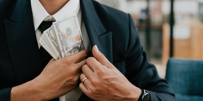 Closeup conceptual photo of bribed man putting money in the suit pocket. banner concept