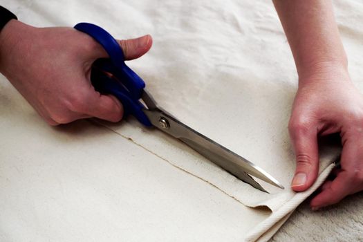 Woman measuring and cutting fabric at home close up view