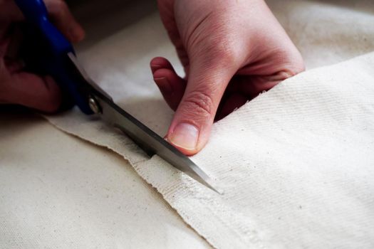 Woman measuring and cutting fabric at home close up view