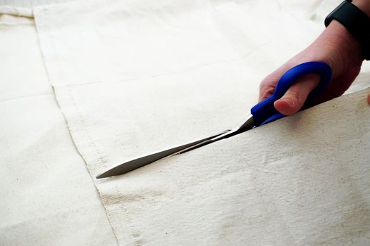 Woman measuring and cutting fabric at home close up view