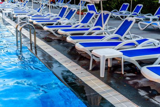 Poolside with blue chezlongs and pool close up view