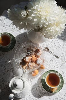 English style tea break, still life with flowers and donuts in the morning sun, homemade cakes, food from above. High quality photo