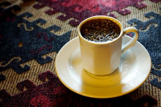 Traditional Menengic coffee on porcelain cup on ethnic table cloth