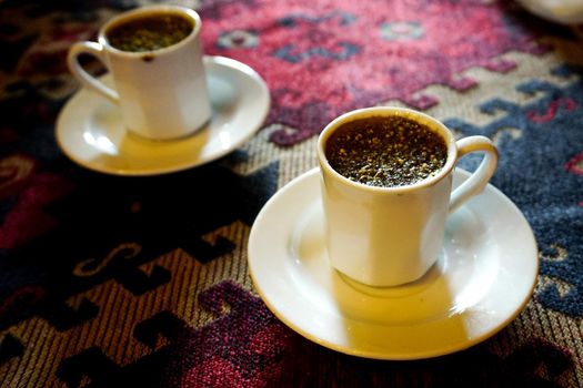 Traditional Menengic coffee on porcelain cup on ethnic table cloth